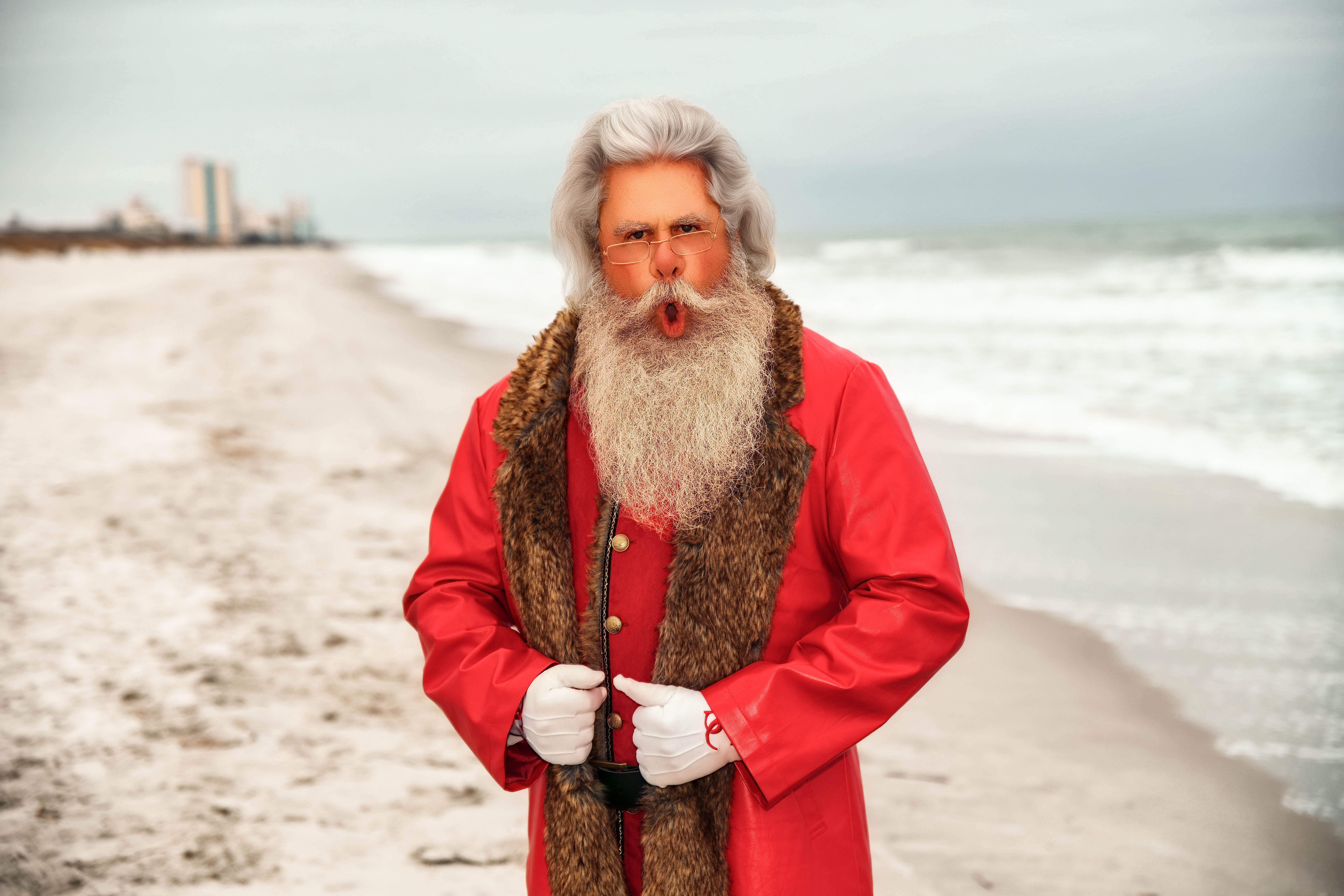 Santa Steve smiling on the beach in his red suit